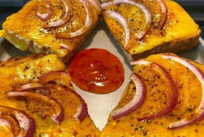 Thumbnail for A toasted bloomer with cheese and red onion, topped with a splash of Henderson’s Relish and served with a sweet chilli dip. 😋