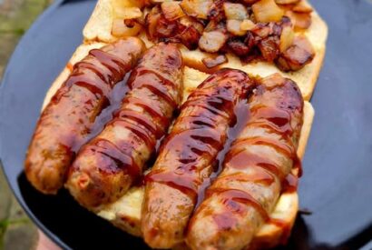 Thumbnail for 🐖 Black Garlic & Red Onion Pork Sosig With White Fried Onions & Brown Sauce on Tiger Bread